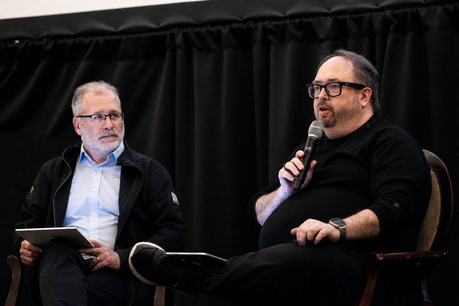 DC in conversation on a panel with a microphone.